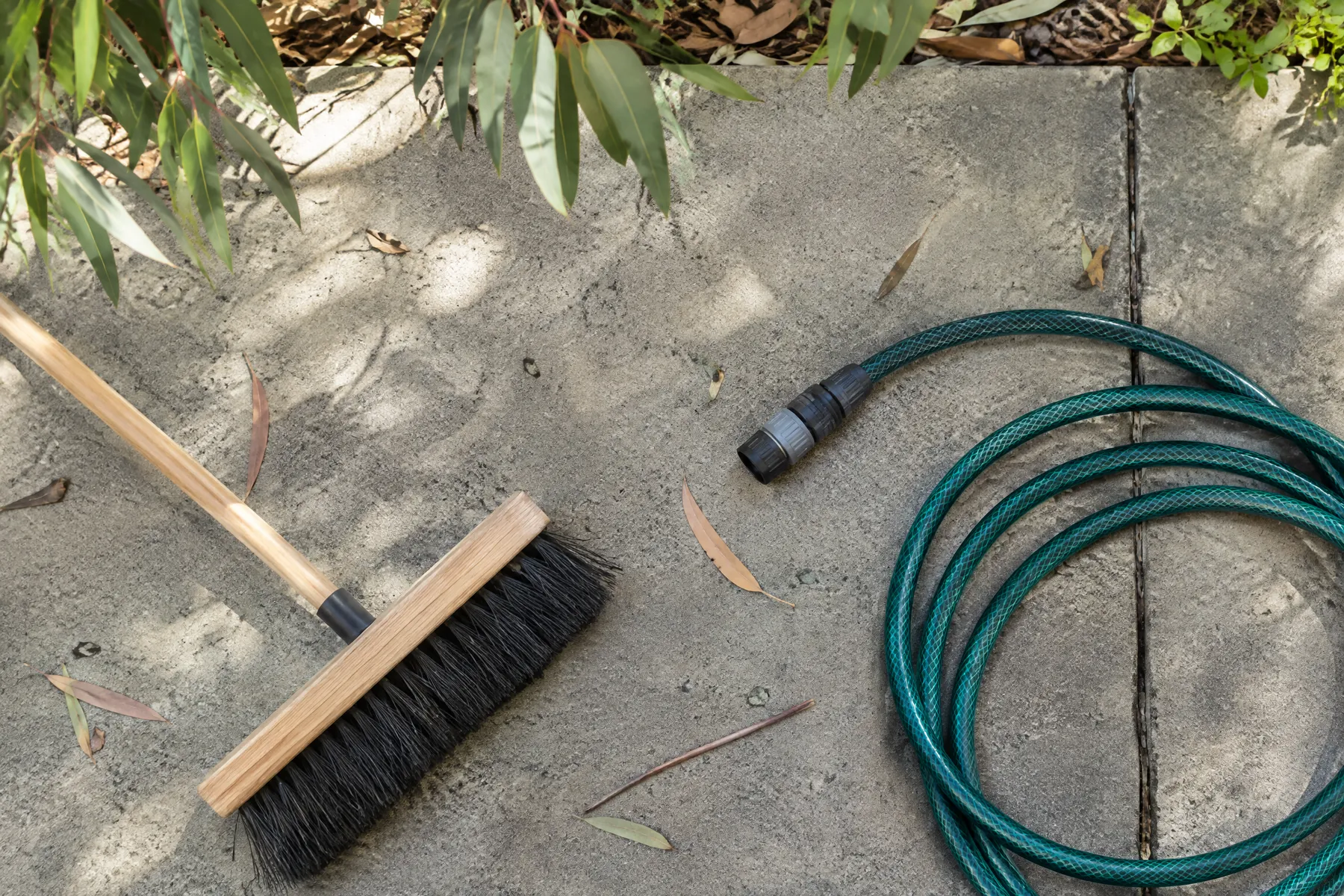 Illustrative soft broom and concrete maintenance tools beside a path; illustrative, not a contractor project